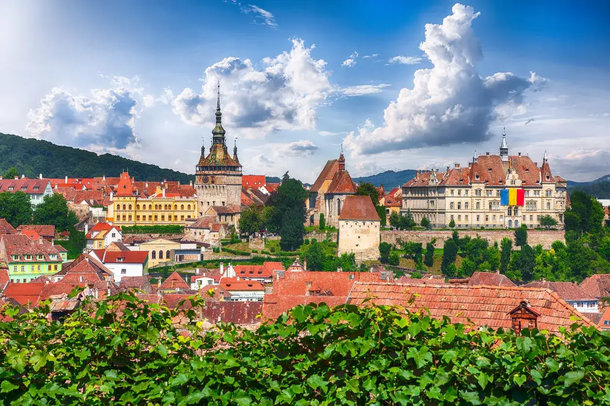 Sighisoara w Rumunii, z wieżą zegarową i kolorową flagą. Ceny noclegów i atrakcji są przystępne.