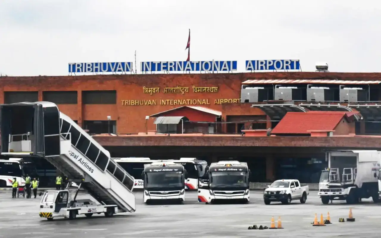 Loty do Nepalu zaczynają się na lotnisku Tribhuvan International Airport w Katmandu. Widoczne autobusy i schody lotnicze czekają na pasażerów.