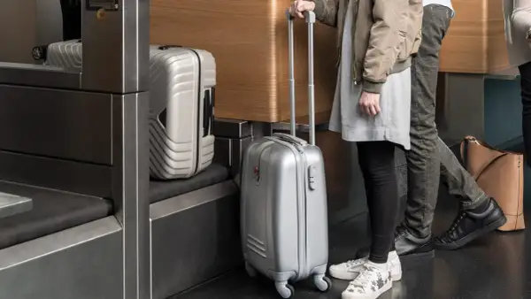 Osoby z bagażem podręcznym Austrian Airlines czekają w kolejce. Srebrne walizki gotowe do podróży.