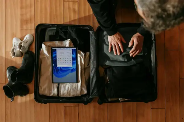 Pakowanie walizki na podróż. Sprawdzam wymiary bagażu rejestrowanego 20 kg Wizzair na tablecie, obok leżą buty i ubrania.