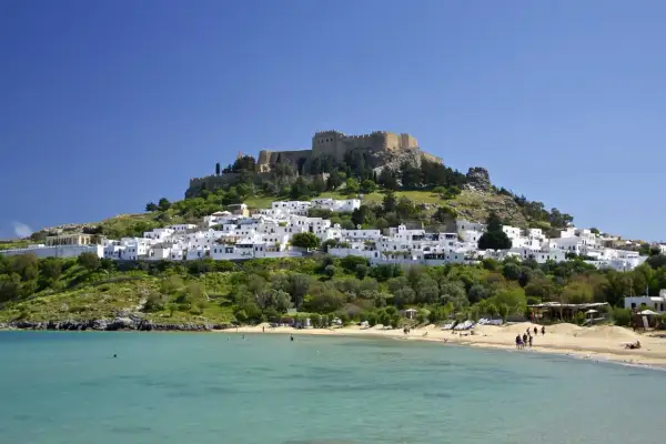 Piękna pogoda na Rodos w maju. Białe domki Lindos i akropol na wzgórzu, plaża i turkusowe morze.