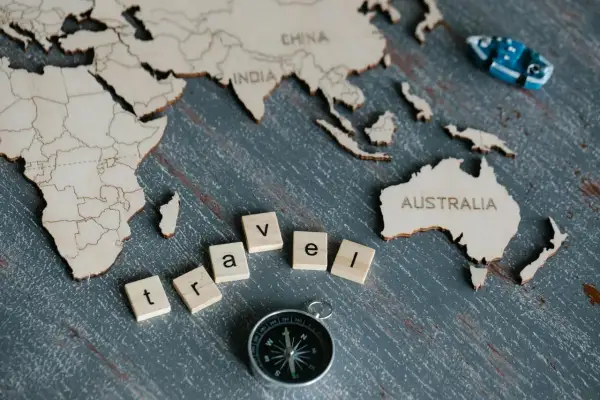 Drewniana mapa świata z napisem "AUSTRALIA" i literami "travel". Ciekawe ciekawostki o Australii czekają na odkrycie!