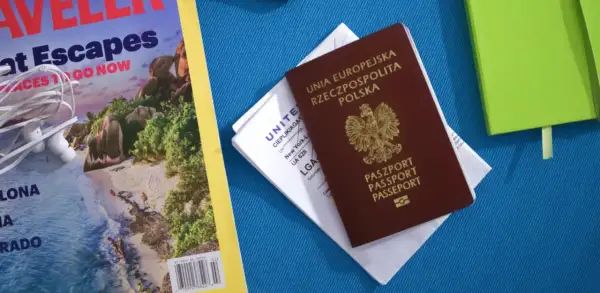 Polski paszport i bilet lotniczy na podróż do Kanady. Obok magazyn podróżniczy i zielony notatnik.